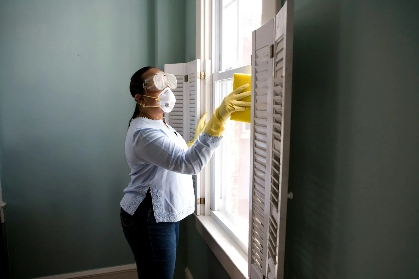 A Lux housekeeper wiping plantation shutters slat by slat